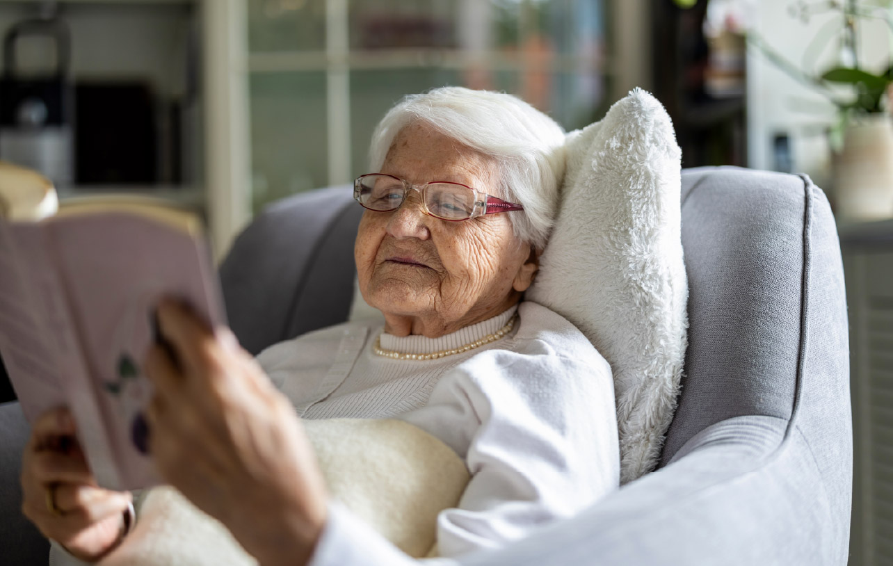 Elderly woman lying on the couch reading
