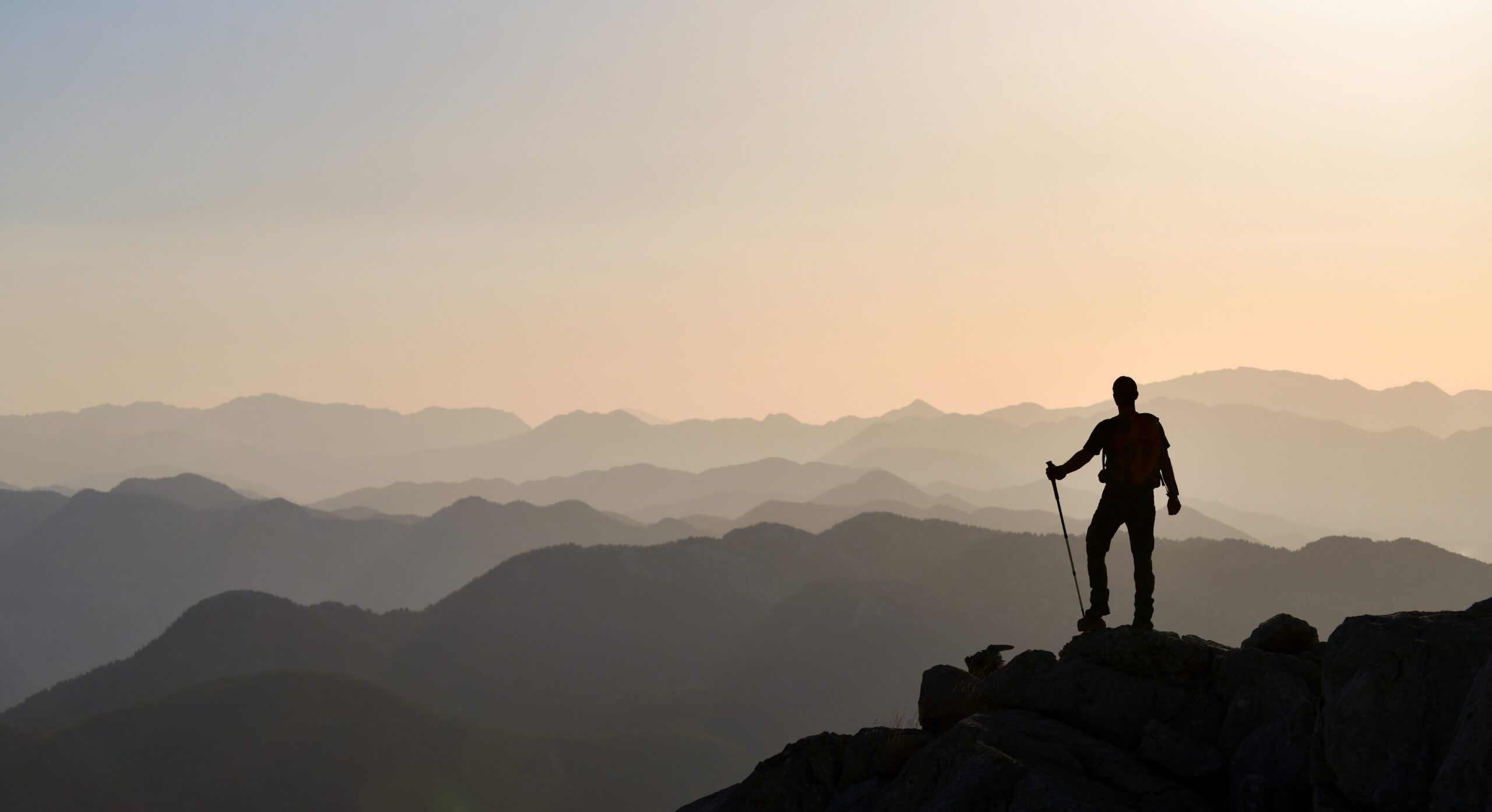 Wide angle shot of a hiker on a mountain looking down on a view